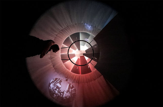 person standing beneath a light installation with fabric. Photo. 